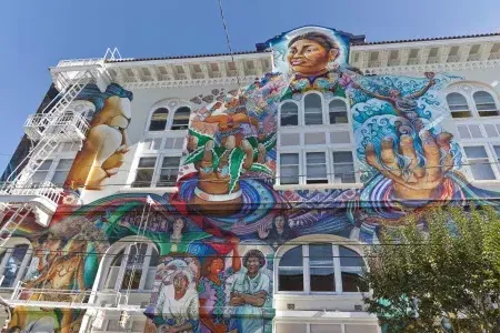 Um mural colorido e grande cobre a lateral do Edifício das Mulheres no Distrito Mission, em São Francisco.