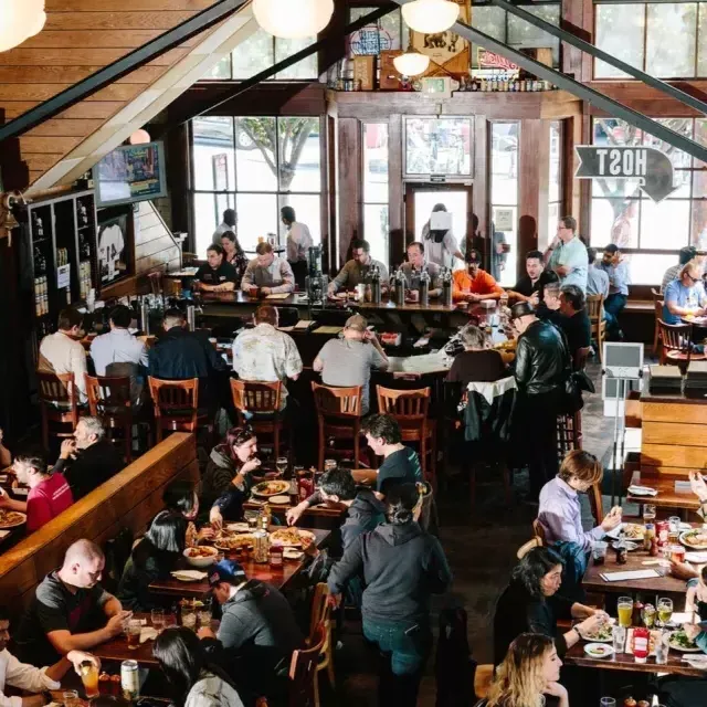 Clientes comem e bebem dentro da 21st Amendment Brewery em São Francisco.